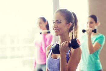 a group of women exercising with dumbbells in a gym at Vibe Apartments at Arbour Lake in Calgary, AB, T3G 4J2